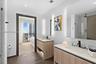 Dual wood-finish floating vanities featuring stone-style countertops, rectangular undermount sinks, matte black fixtures, and integrated LED-backlit m