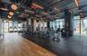 Industrial-style fitness center featuring floor-to-ceiling windows, exposed structural ceiling, wood-finish flooring, rubberized workout surfacing, an