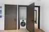 Laundry closet featuring a built-in front-load washer, dark wood-finish interior doors with matte black hardware, and wood-finish flooring