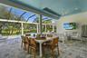Covered lanai featuring a tray ceiling with recessed lighting, integrated ceiling fan, paver flooring, and a screen enclosure overlooking a swimming p