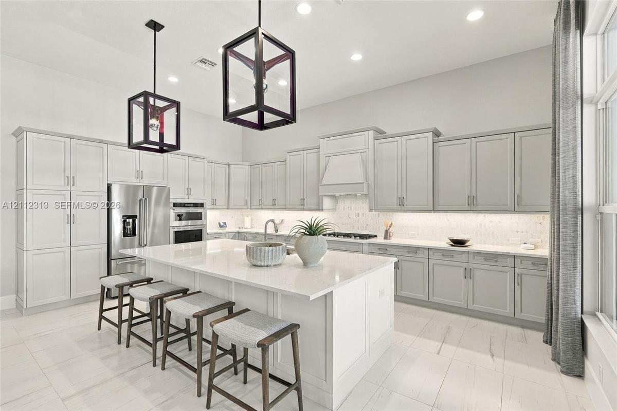Kitchen featuring shaker-style cabinetry, quartz countertops, a central island, recessed lighting, and geometric pendant fixtures