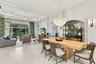 Open-concept living space featuring high tray ceilings, recessed lighting, expansive tile flooring, and a crystal chandelier