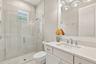 Bathroom featuring a vanity with a white countertop and undermount sink, a walk-in shower with a glass enclosure, floor-to-ceiling tilework, and a mul