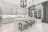 Kitchen featuring light-toned cabinetry, a large central island with a solid surface countertop, tile flooring, recessed lighting, and geometric penda