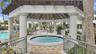 Outdoor gazebo featuring a circular in-ground spa, decorative columns, timber-frame roof structure, and paved stone surround