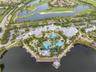 Aerial perspective of a multi-structure facility featuring a complex of resort-style swimming pools, expansive paved sun decks, a waterfront gazebo, a