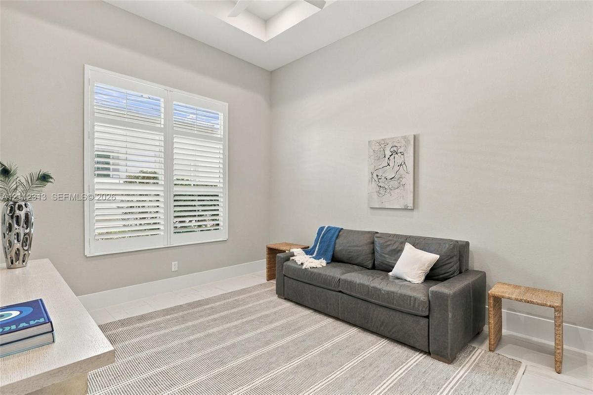 Room interior featuring a tray ceiling, plantation shutters, and neutral wall color