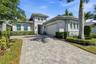 Single-story residence featuring a neutral stucco exterior, paver driveway, multi-pane windows, and a multi-tiered roofline with decorative corbels
