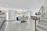 Open-concept interior featuring large-format tile flooring, vaulted ceilings, recessed lighting, and a staircase with stainless steel cable railing