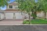 Two-story residence featuring a tile roof, dual-bay garage, paved driveway, and double-entry doors