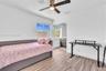 Room featuring wood-finish flooring, a ceiling fan with integrated lighting, dual-pane windows, and a sliding mirrored closet door