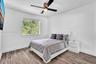 Bedroom featuring wood-finish flooring, a contemporary ceiling fan with integrated lighting, and a single-pane window