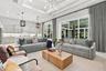 Open-concept living space featuring high coffered ceilings with recessed lighting, oversized sliding glass doors, neutral cabinetry with a stone-finis