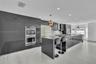 Contemporary kitchen featuring high-gloss cabinetry, stainless steel double wall ovens, a large kitchen island with quartz countertops, recessed light
