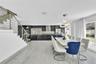 Open-concept interior featuring large-format tile flooring, high-gloss cabinetry, stainless steel range hood, stainless steel horizontal railing stair