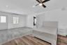 Interior space featuring wood-finish flooring, recessed lighting, ceiling fan with integrated light, and wall-mounted climate control unit