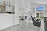 Vaulted ceilings, large-format tile flooring, a metal stair railing, and expansive glass window panels with exterior access