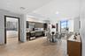 Open-concept interior featuring wood-finish tile flooring, custom flat-panel cabinetry, stainless steel kitchen appliances, and floor-to-ceiling windo