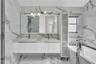 Floating double vanity with integrated rectangular sinks, stone-finish countertop, full-height frosted glass cabinetry, and floor-to-ceiling vein-patt
