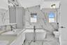 Bathroom featuring floor-to-ceiling large-format tile with decorative veining, freestanding soaking tub with floor-mounted faucet, rectangular vessel 
