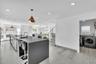 Kitchen featuring a large island with a solid surface countertop, dual undermount sinks, geometric pendant lighting, and tile flooring