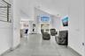 Vaulted ceilings, large-format tile flooring, double-door glass entrance with arched transom window, and metal cable railing