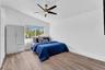 Vaulted ceiling featuring a central five-blade ceiling fan, wood-finish flooring, and a large picture window