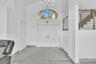 Double-door entryway featuring vaulted ceilings, a prominent arched transom window, a contemporary multi-arm chandelier, and metal horizontal-bar rail