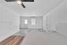 Interior space featuring mixed-material wood-finish flooring, recessed lighting, a modern ceiling fan, and a wall-mounted climate control unit