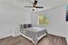 Room featuring wood-finish flooring, a neutral color palette, a modern ceiling fan with integrated lighting, and a window with exterior greenery