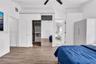 Wood-finish flooring, vaulted ceilings with a matte black ceiling fan, and built-in closet system with mirrored sliding doors
