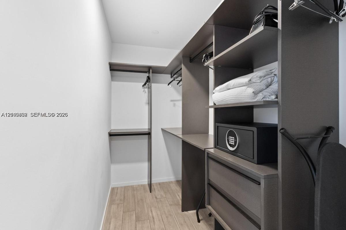 Custom closet system featuring dark wood-finish cabinetry, integrated shelving, hanging rods, and two soft-close drawers, complemented by wood-finish 