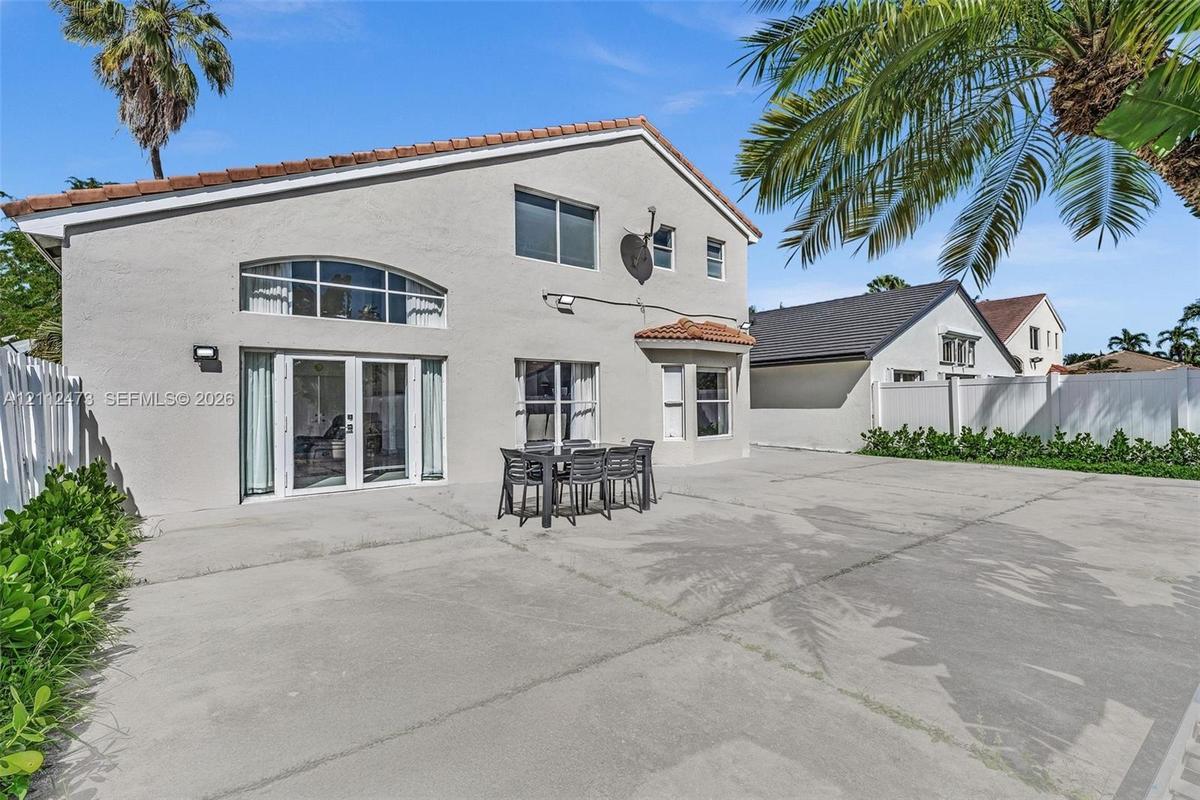 Stucco exterior featuring a large concrete patio, arched transom window, French doors, and bay window architecture