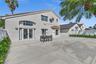 Stucco exterior featuring a large concrete patio, arched transom window, French doors, and bay window architecture