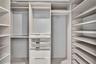 Customized closet organization system featuring adjustable shelving, integrated garment rods, and built-in drawers with glass-front paneling