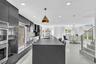 Kitchen featuring high-gloss cabinetry, expansive waterfall-edge island, built-in double ovens, recessed lighting, and large-format tile flooring