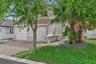 Stucco exterior featuring a two-car garage, red clay tile roofing, decorative trim detailing, and a paved brick driveway