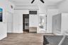 Wood-finish flooring, vaulted ceiling with a matte black fan, sliding mirrored closet door, and built-in closet organization system