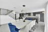 Open-concept kitchen featuring high-gloss dark cabinetry, integrated stainless steel appliances, and tile flooring