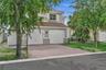 Two-story exterior featuring a clay tile roof, stucco siding, arched garage doors, a paved driveway, and decorative window shutters