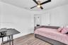 Room featuring wood-finish flooring, white walls, and a ceiling fan with integrated lighting