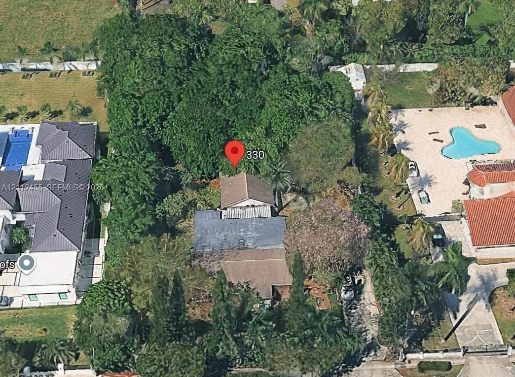 Aerial perspective showcasing a parcel with mature canopy trees, dense perimeter vegetation, and a multi-section roofline