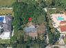 Aerial perspective showcasing a parcel with mature canopy trees, dense perimeter vegetation, and a multi-section roofline