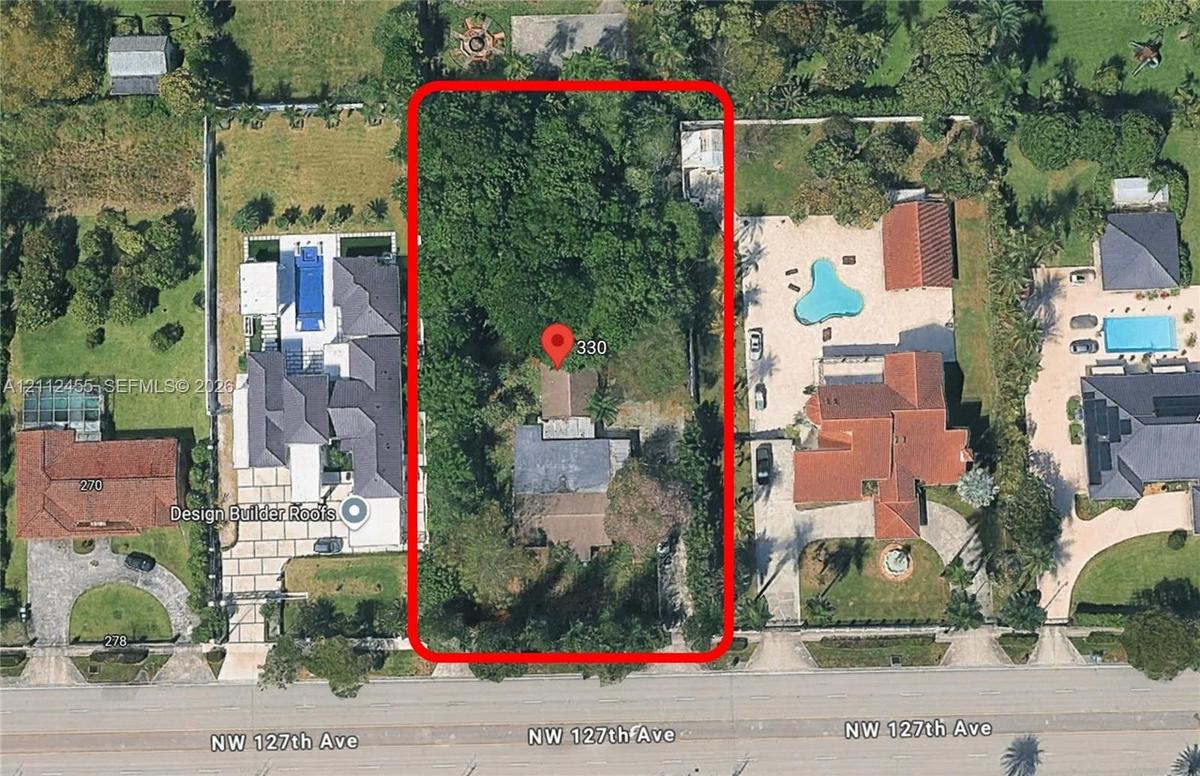 Aerial view of a deep rectangular lot featuring mature vegetation, dense tree canopy, and an existing residential structure