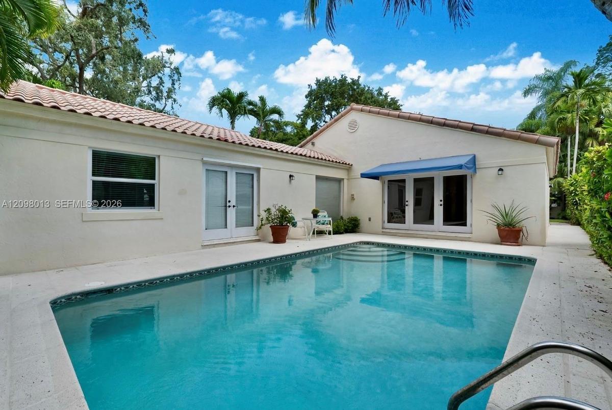 In-ground swimming pool with a concrete surround, tile roof, and multiple glass-paned double doors