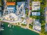 Aerial perspective of a multi-level waterfront estate featuring a private deep-water dock, extensive rooftop terrace space, and hardscaped circular mo