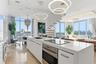 Kitchen featuring a center island with a stone countertop, built-in cooktop, and under-counter oven, floor-to-ceiling windows, polished stone flooring