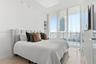 Floor-to-ceiling windows, light-toned wood-finish flooring, built-in shelving, and high-contrast urban scenery