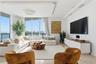 Living area featuring floor-to-ceiling windows, custom recessed tray ceiling with integrated lighting, polished stone flooring, and built-in low-profi