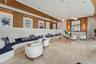 Expansive lobby featuring polished stone flooring, wood-paneled walls, a custom curved built-in seating structure, recessed ceiling lighting, and a mo